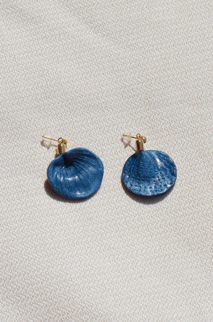 Blue earrings on a light gray fabric background