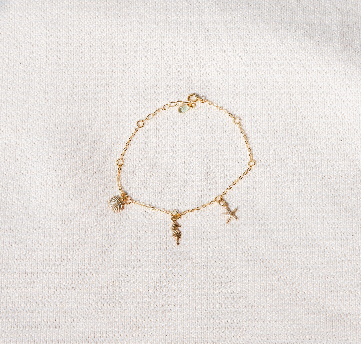 Gold bracelet with charms on a light gray background