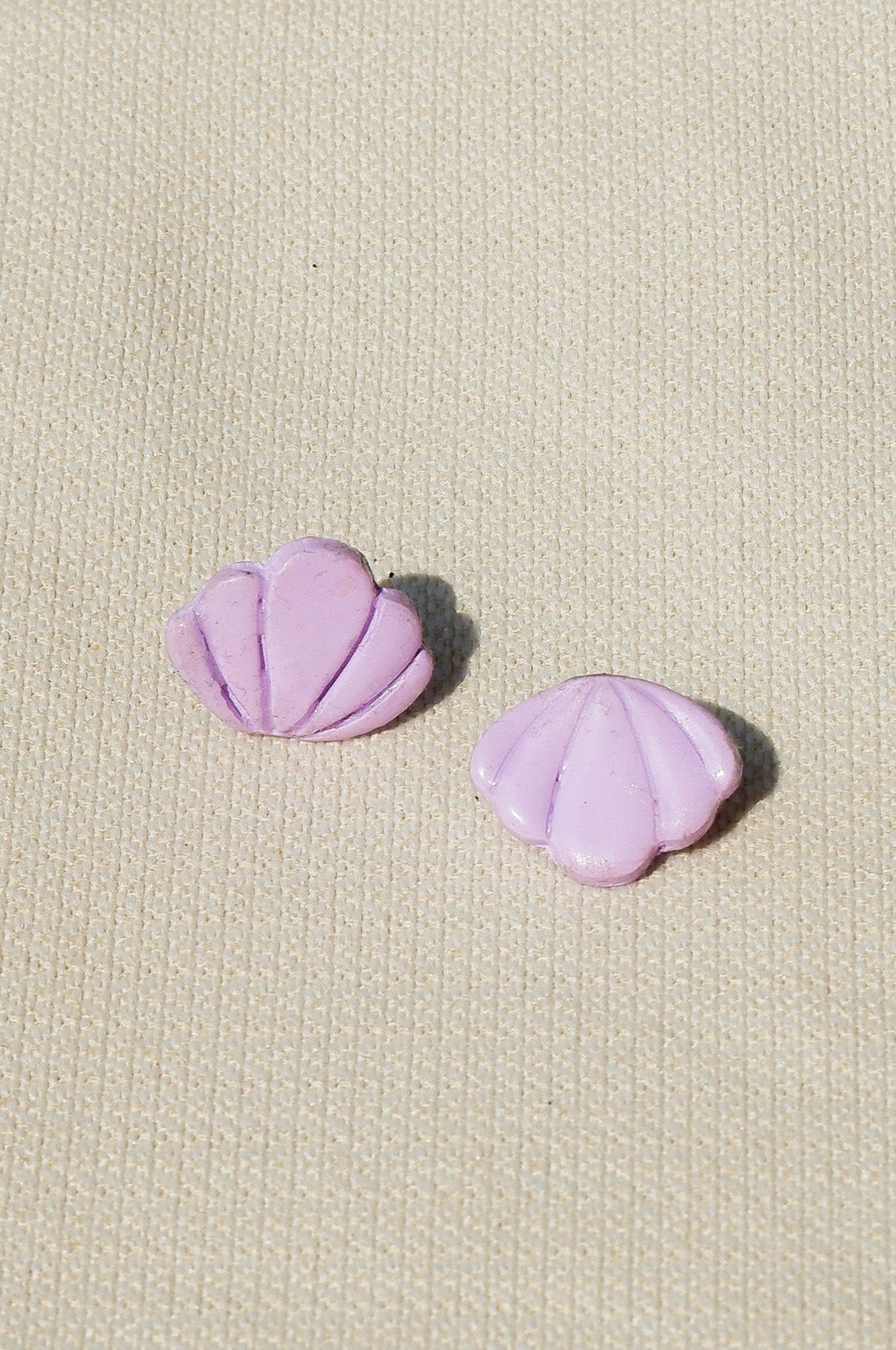 Pair of Lilac earrings on a beige textured background
