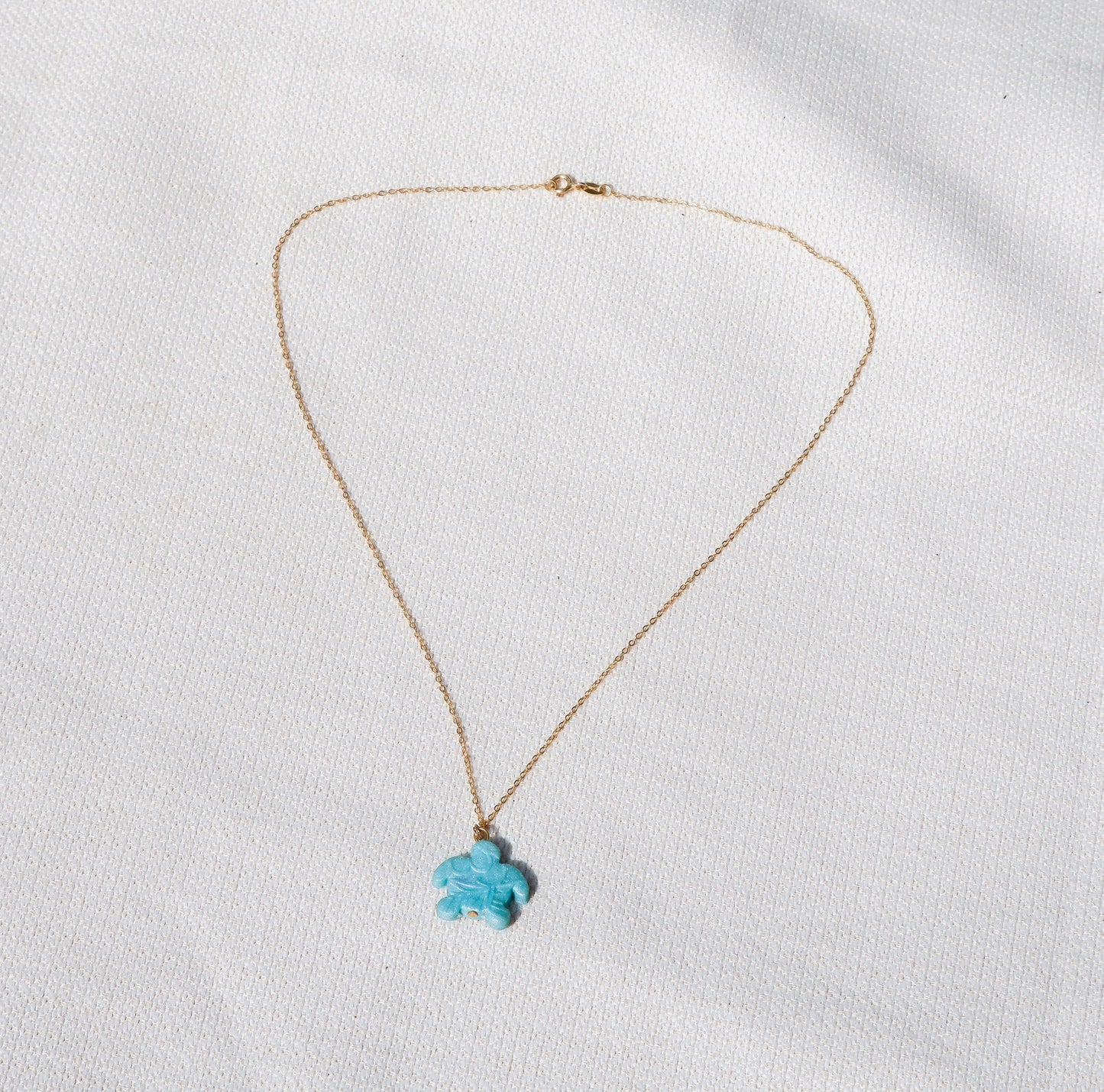 Gold necklace with a turtle pendant on a white background
