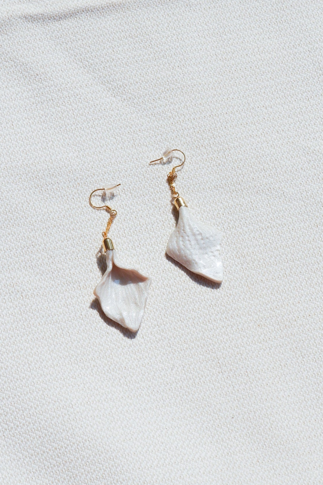 Pair of white teardrop earrings on a light gray background