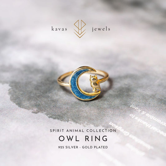 Gold and blue owl ring on a textured surface with 'kavas jewels' branding.