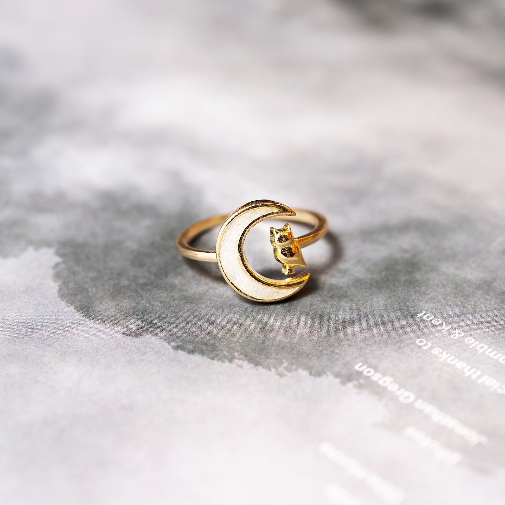 Gold ring with a owl design on a textured surface