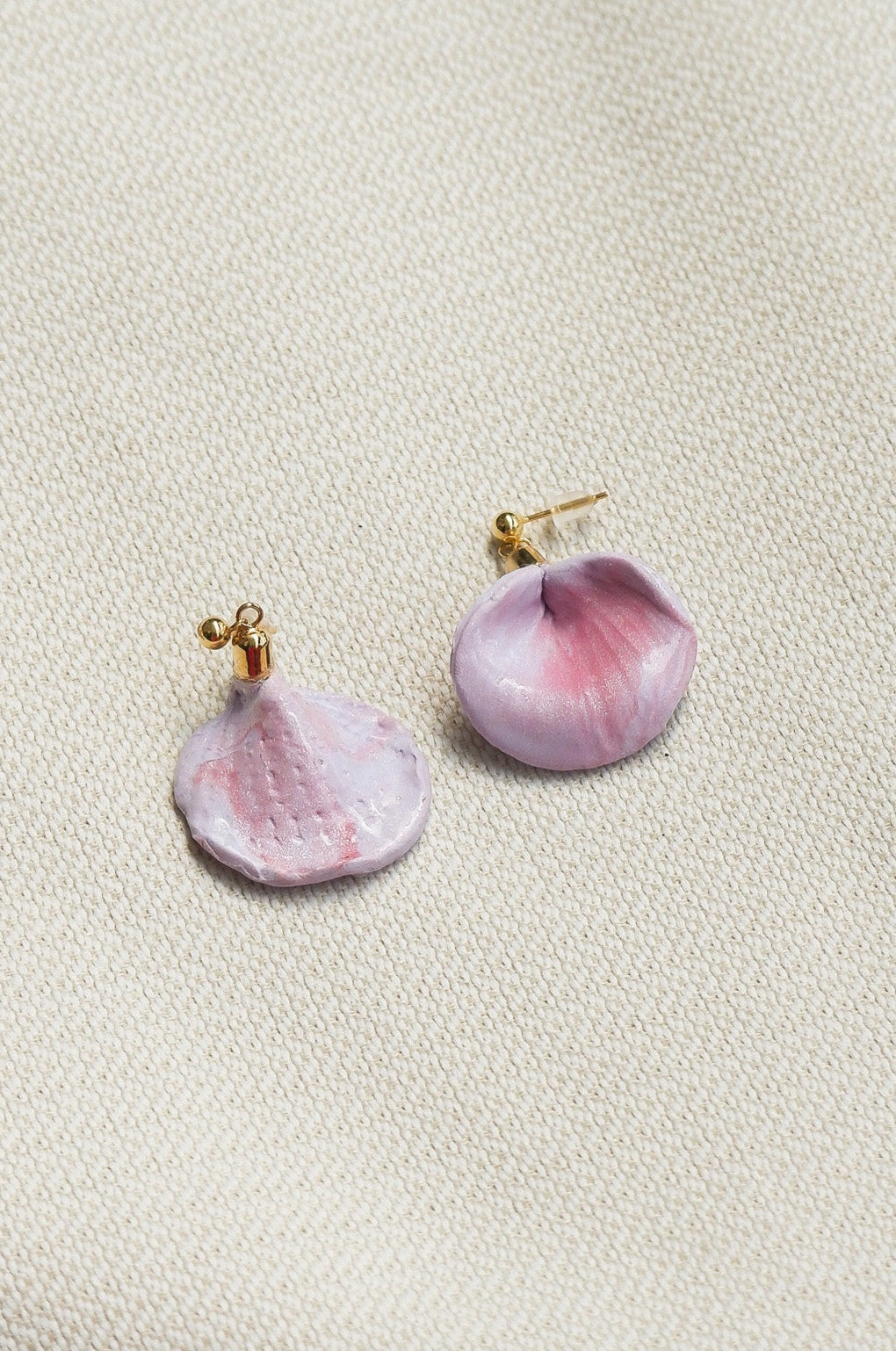 Pair of pink and gold earrings on a light beige background