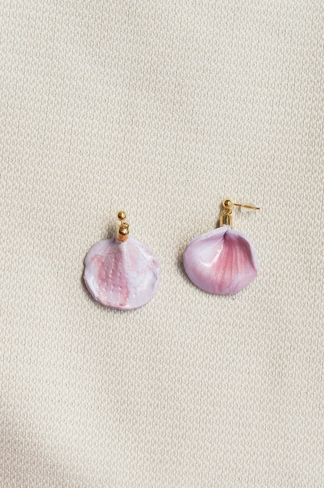 Pink petal-shaped earrings on a light beige background