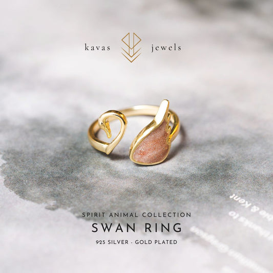 Gold-plated swan ring with 'kavas jewels' branding on a gray background