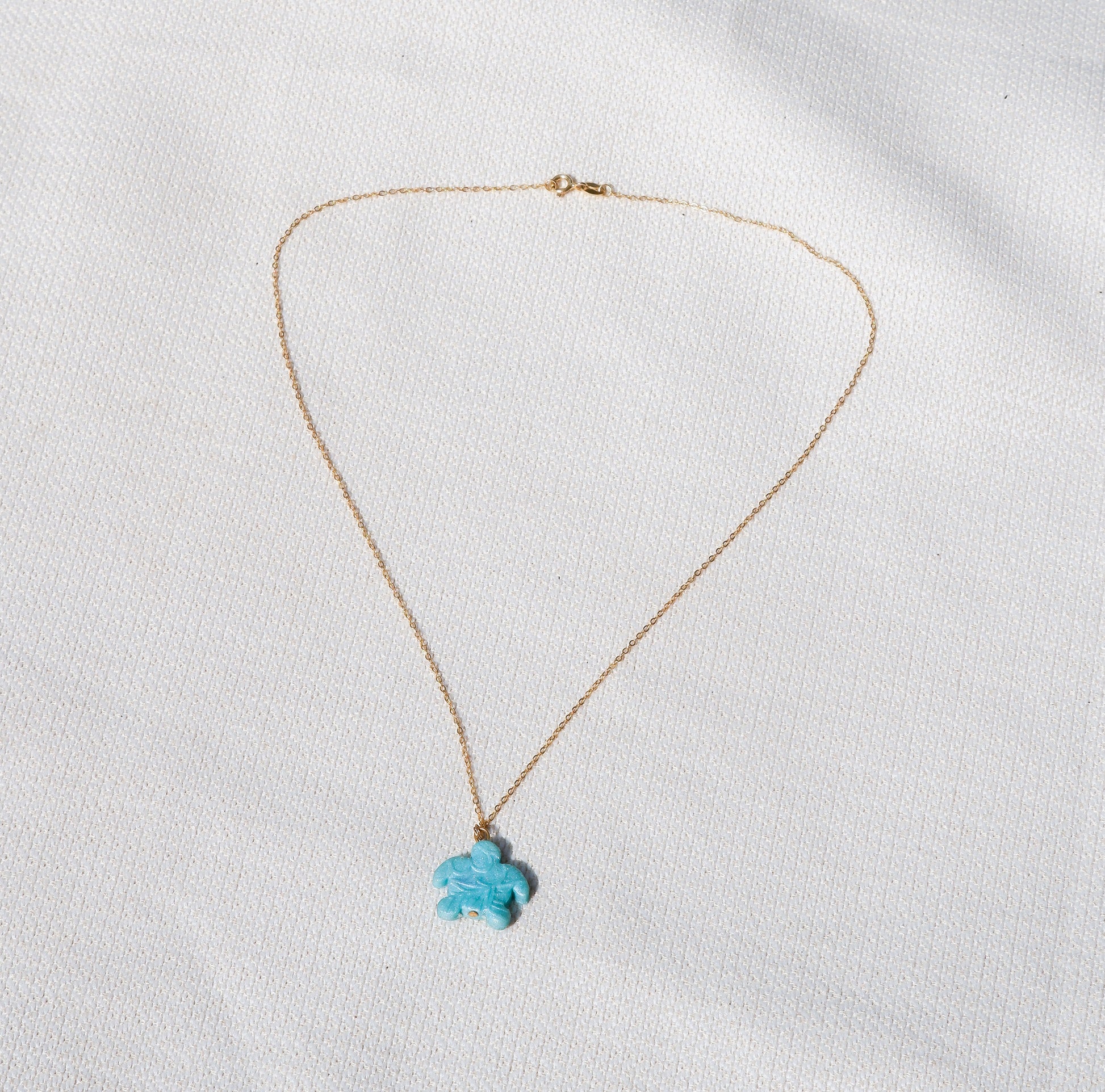 Gold necklace with a turtle pendant on a white background